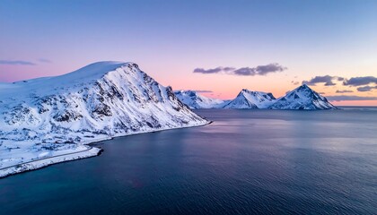 Aerial view of snow-covered mountains by calm ocean at dusk