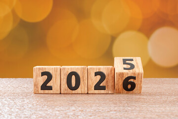 Wooden blocks switching from 2025 to 2026 on a table with bokeh background