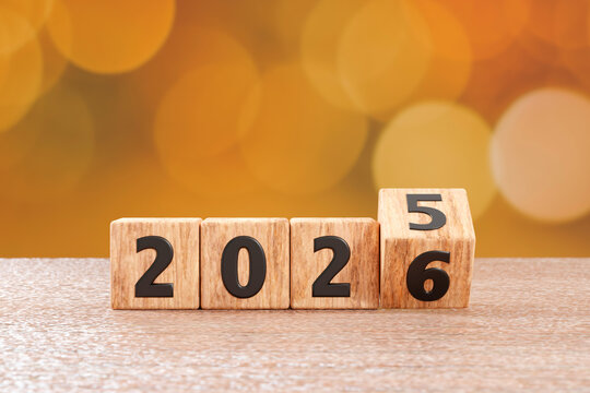Wooden blocks switching from 2025 to 2026 on a table with bokeh background