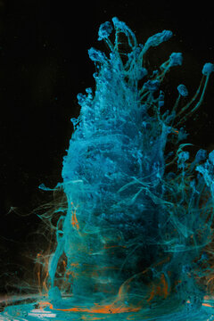 Bright ink swirls in water forming tornado shapes