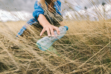 Woman removing plastic bottle from field for environmental protection