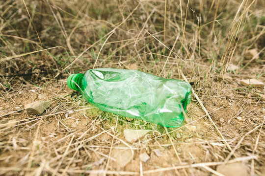 Plastic bottle in dry grass highlights environmental pollution outdoors