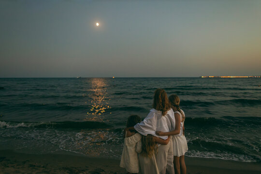 Family bonding on the beach watching the moon at peaceful evening