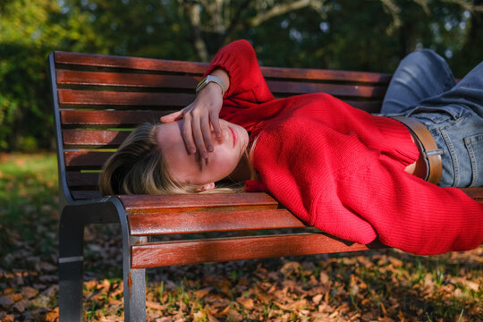 Woman relaxing on park bench in red sweater practicing mindfulness