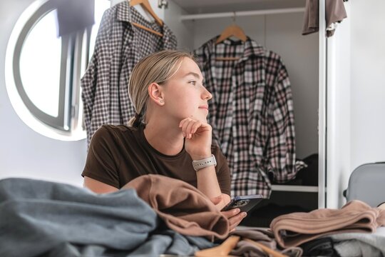Woman organizing capsule wardrobe for travel planning indoors