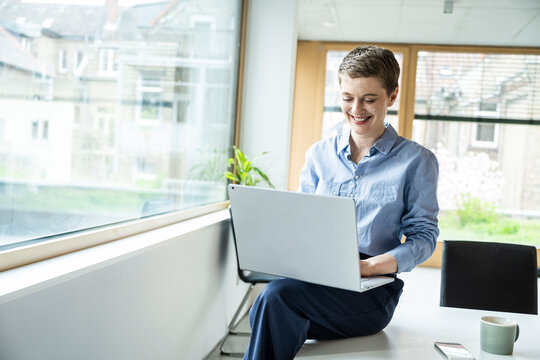 Smiling woman working on a laptop in a modern office setting