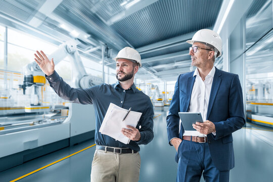 Manager and engineer in factory with tablet discussing production automation