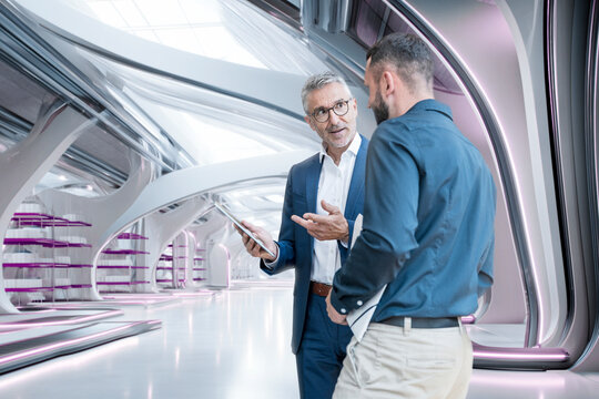 Manager discussing teamwork with colleague in futuristic office