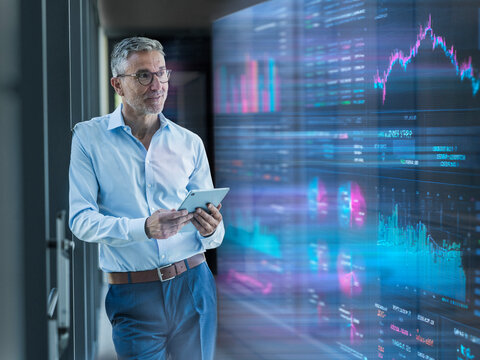 Engineer analyzing financial data on tablet in server room