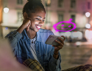 Smiling woman using mobile phone to chat with AI bot at night outdoors