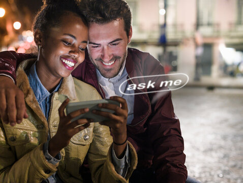 Smiling friends using mobile AI chat bot outdoors at night