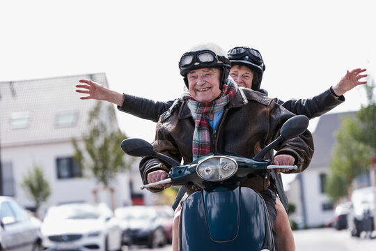 Smiling couple riding scooter outdoors having fun together