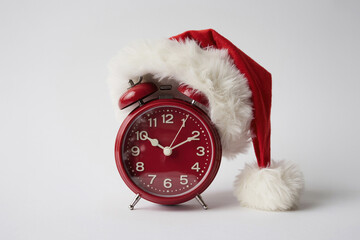 A small red alarm clock with a Santa hat.