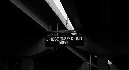 Bridge Inspection Warning Sign Displayed Beneath a Concrete Elevated Structure in Black and White