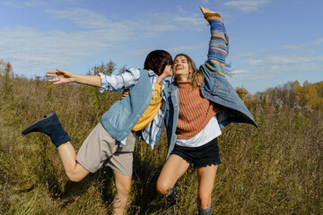 Two friends dancing and laughing together outdoors in a field
