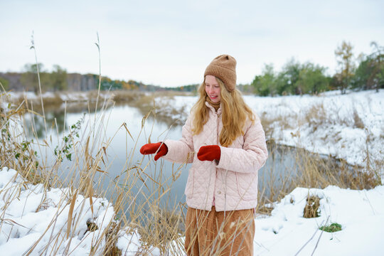 Woman in warm clothing smiling and playing outdoors in snowy winter nature