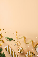 Items for Christmas gift wrapping. Golden and white striped wrapping paper, ribbon, scissors on beige backdrop. Copy space.