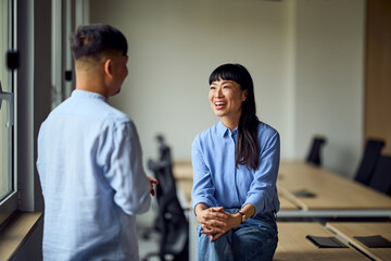 Two Professionals in Modern Office Share Laughs During Casual Business Meeting