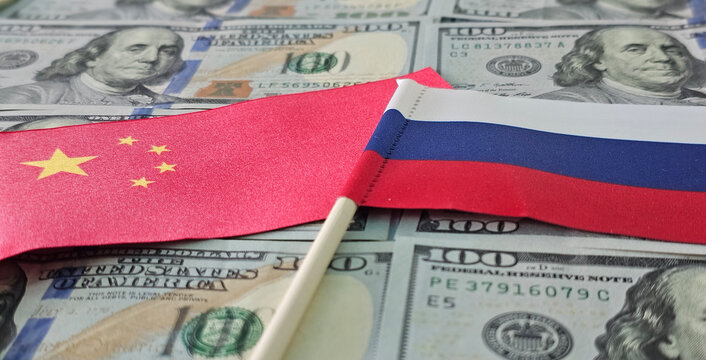Chinese and Russian flags lying on a stack of US dollar bills concept