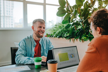 Happy businessmen sitting with laptops and having discussion in office