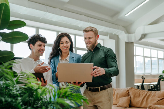 Colleagues discussing work on a laptop in a modern office environment - Powered by Adobe