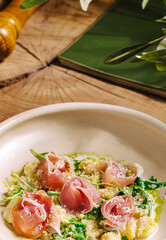 Delicious plate of pasta with prosciutto and greens served in a cozy setting