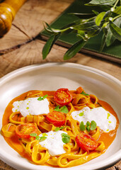 Delicious fettuccine with cherry tomatoes and creamy sauce on a rustic table