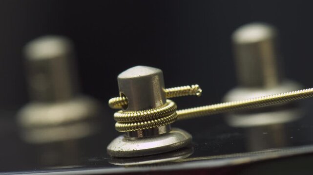 Closeup view of winding a new string onto guitar tuning peg