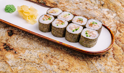 Fresh sushi rolls served on a white plate with wasabi and ginger