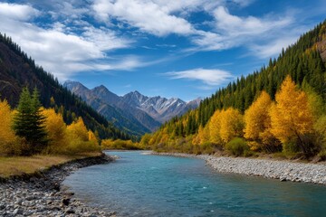 River flows through a valley flanked by trees in autumn colors with snowcapped mountains in the background
