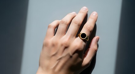 Hand with Elegant Gold Signet Ring Against Light and Shadow Back