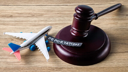 Deportation concept with a judge's gavel and a toy airplane on a wooden surface, symbolizing legal migration and immigration issues.