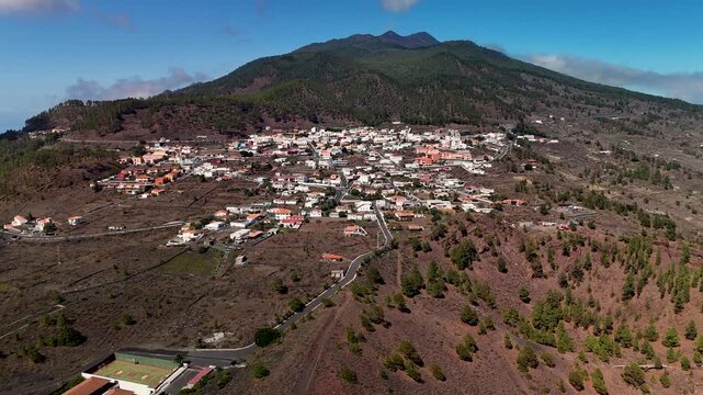 Aerial drone pan out revealing the white houses of Los Canarios (Fuencaliente) town and the vast volcanic landscape of southern La Palma, Canary Islands, Spain.
