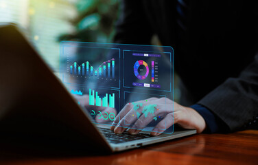 Business professional working on a laptop with futuristic digital dashboards displaying analytics, financial data, charts, and global metrics, highlighting advanced data analysis and innovation.