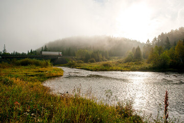 a foggy morning on the river, a truck driving on the highway