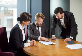 Focused business people discussing documents during meeting about important business decisions. Colleagues at round table brainstorming discussing contract agreement and planning business strategy.