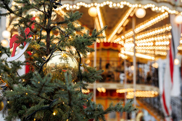 Christmas tree with a golden bauble and a red wooden horse. Carousel is in the background.