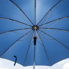 White umbrella on blue sky background, an abstract protection from the sun or rain