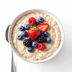 Overhead view of a healthy bowl of oatmeal topped with fresh strawberry, blueberry, raspberry, and blackberry isolated on white background
