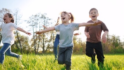 Fototapeta premium group of children running in the park. happy family baby kid dream concept. kindergarten. children hands to the sides play pilots plane run on the lifestyle grass in the summer in the park
