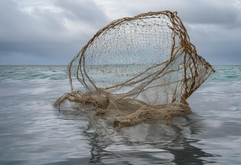 Large, abandoned fishing net ominously floats on the grey, rippling surface of the ocean. 