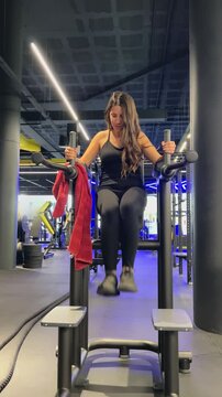 Chica haciendo elevaciones de piernas en el gym