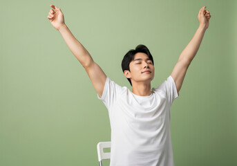 Relaxed man in white tshirt stretching with closed eyes on green background