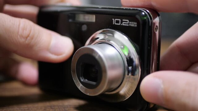 Digital Photo Camera in Photographer Hands on Table, Built-In Lens Focusing with Audible Clicks, Precision Optical Adjustment, Mini Camera Operation, Realistic Household Gadget Focus Sound