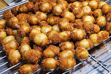 Crispy fried Thai fermented pork and rice sausages or Sai Krok Isan on a metal rack.