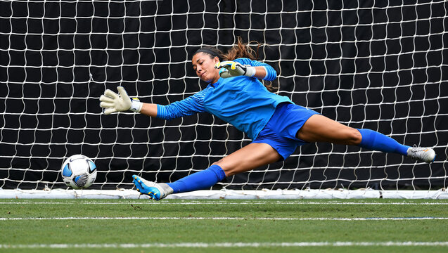 Determined female English goalkeeper diving to save ball in intense moment. Concept of defense, athletic reflexes, sports training materials, competitive football visuals, emotional tension.