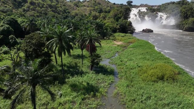 Aerial side view of Binga Falls, Angola, with cascading water and green riverbanks under bright tropical sunlight in a pristine African environment