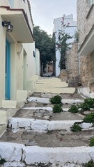 Scenic street in Alonnisos island, Greece, with traditional stone pathways, whitewashed houses, colorful wooden doors, and blooming bougainvillea. Peaceful Mediterranean atmosphere, narrow alleys with