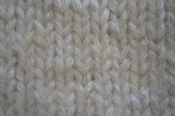 Cream knitted wool fabric texture, close-up white wool fabric showing soft yarn fibers and a detailed looped texture. The image highlights the warm, cozy appearance typical of knitted textiles used in