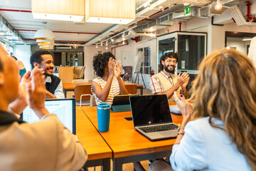 Diverse colleagues clapping at successful business meeting in office